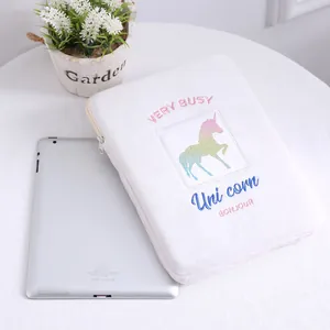 Detalle de funda de felpa blanca para iPad con bordado de unicornio y cierre de cremallera