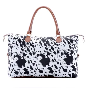 Détail du sac fourre-tout en toile à motif vache avec anses en cuir et fermeture éclair