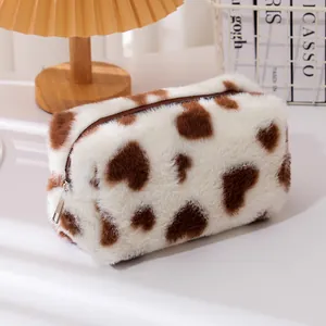 Detalle de bolsa de cosméticos de felpa suave con estampado de corazón de vaca y cremallera