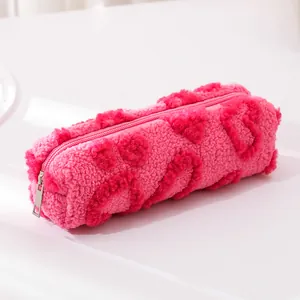 Pink plush pencil case with heart pattern and silver zipper on white background