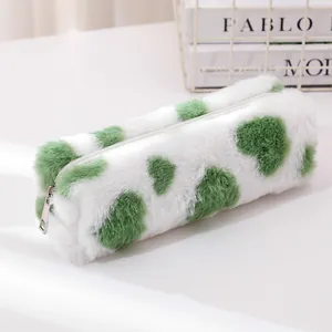 Detail of white plush pencil case with green heart pattern and silver zipper closure