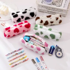 Flat lay of colorful plush pencil cases with heart and cow patterns for large capacity storage