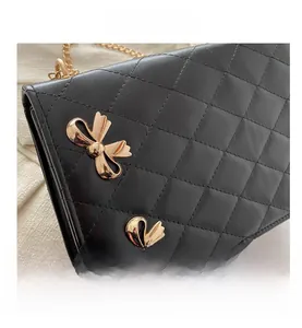 Détail d'un sac bandoulière noir matelassé avec des nœuds dorés et une bandoulière chaîne