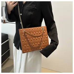 Detail of brown quilted diamond pattern bag with gold chain strap and leather handle
