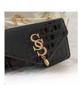 Detail der schwarzen Umhängetasche mit Krokoprägung, goldener S-Schnalle und Quaste