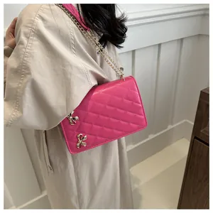 Vue détaillée du sac rose à motif matelassé avec nœuds dorés et bandoulière chaîne