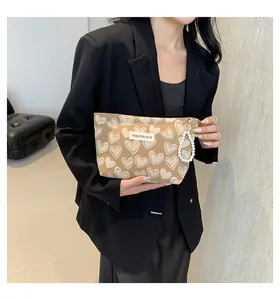 Detail of cute heart-print cosmetic bag with elegant pearl handle and fashion label