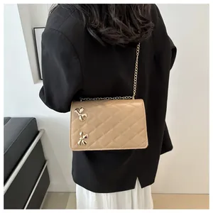 Vue arrière d'un sac bandoulière beige matelassé avec nœuds dorés sur un mannequin