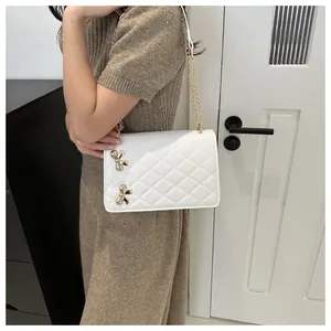 Vue détaillée d'un sac bandoulière blanc matelassé avec nœuds dorés et chaîne