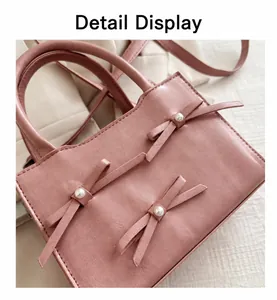 Detail of pink faux leather bag with bow ornaments and white pearl accents on the surface