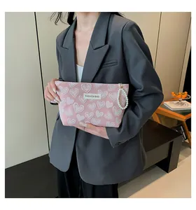Pink heart patterned makeup bag with elegant pearl handle and fashion label close-up