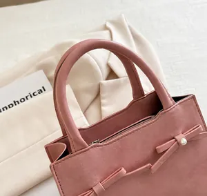 Detail of pink pearl bow handbag featuring a circular top handle and fine stitching