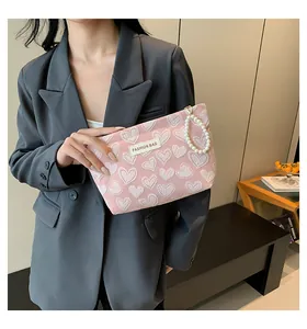 Detail of pink heart-patterned cosmetic bag with elegant pearl strap and texture