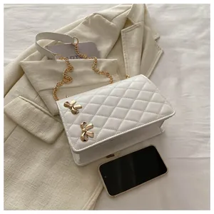 Détail du sac bandoulière blanc matelassé avec nœuds dorés et bandoulière chaîne
