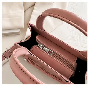 Detail of pink leather handbag showing smooth metal zipper closure and black inner lining