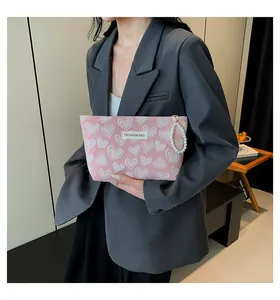 Detail of pink heart-patterned cosmetic bag with pearl handle and fashion label