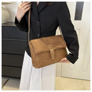 Gros plan du sac cabas en cuir marron avec texture vintage et boucle dorée chic