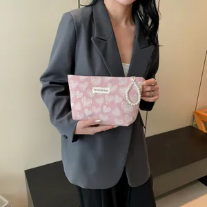 Pink heart embossed makeup bag with pearl handle shown on a modern office desk background