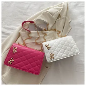 Détail de sacs bandoulière matelassés avec nœuds dorés et chaînes sur blazer beige