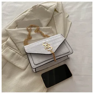 Detailansicht der weißen Tasche mit Steinmuster, goldenem SS-Logo und Fransenquaste
