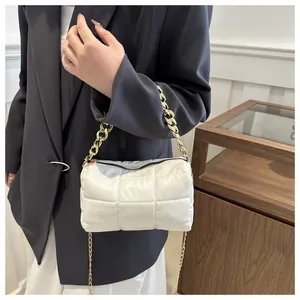 Detail of white quilted puffy barrel bag with gold chunky chain handle and shoulder strap