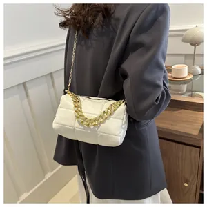 Detail of white quilted puffy shoulder bag with thick gold chain on a woman in gray blazer