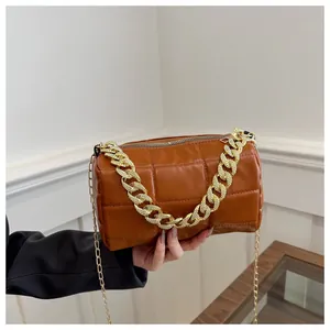 Detail of caramel brown quilted cylinder bag with chunky gold chain and metal zipper