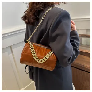 Close-up of brown quilted pillow bag with chunky gold chain handle and shoulder strap