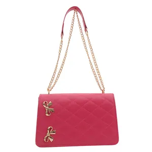 Sac bandoulière matelassé fuchsia avec chaîne dorée et détails nœuds sur fond blanc