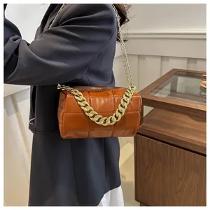 Detail of a brown quilted pillow bag with chunky gold chain and slim shoulder strap
