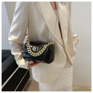 Detail of black quilted puffer bag with gold chunky chain handle and chain shoulder strap