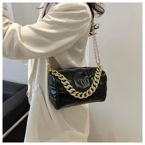 Detailed view of black quilted cylinder bag with chunky gold chain strap and PU texture