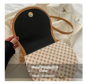 Close-up of saddle bag magnetic snap closure and vintage monogram texture details