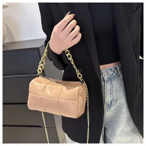 Detailed view of beige quilted barrel bag with chunky gold chain and slim shoulder strap