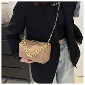 Detail of khaki quilted pillow bag featuring a bold gold chain handle and long strap