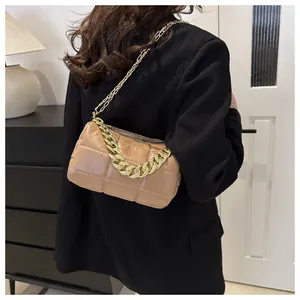 Quilted beige shoulder bag with thick gold chain handle worn over a black blazer