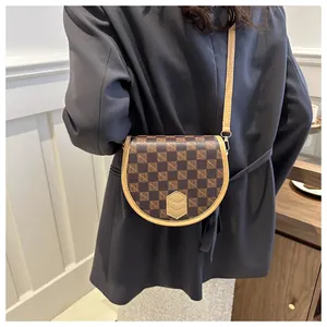 Detail of vintage checkered saddle bag with adjustable light camel crossbody strap