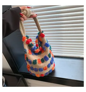 Detail of plush beige bucket bag with colorful tufted dots and knotted strap handle