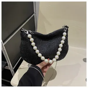 Detail of black rhinestone shoulder bag with large white pearl handle and metal chain