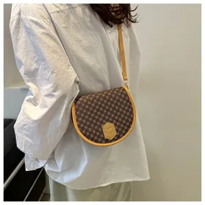 Detail of vintage saddle bag with brown pattern worn over a white shirt