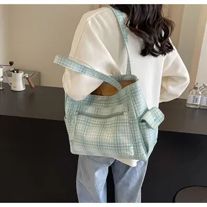 Detail of light green plaid canvas tote bag with front zipper pocket and side flap pocket