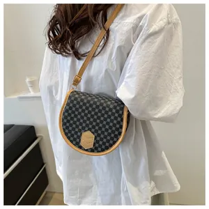 On-body shot of a vintage saddle bag with black geometric pattern and brown leather trim