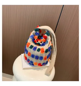 Detailed macro shot of plush bucket bag texture with colorful 3D pom-poms on off-white fabric