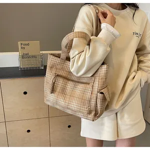 Detail of light brown checkered canvas tote bag with front zipper and side flap pocket
