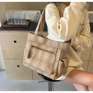 Detail of checkered tote bag showing front zipper pocket and functional side buckle pouch