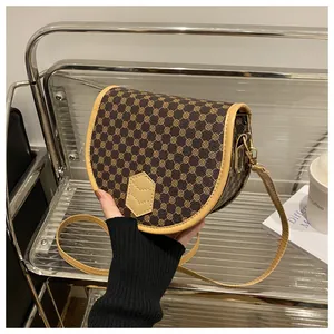 Detail view of vintage brown saddle bag with geometric patterns and golden metal buckles