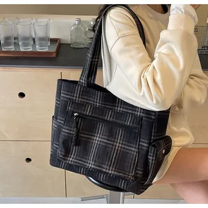 Detailed side view of black and grey plaid tote bag with functional flap pockets