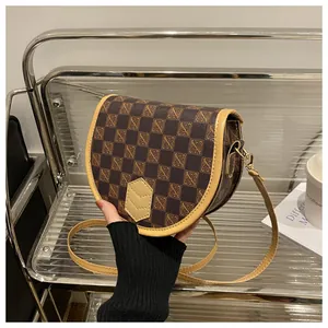 Detail of vintage checkered saddle bag with gold-tone hardware and adjustable strap