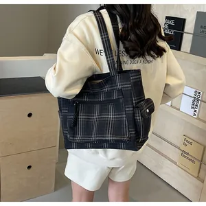 Detail of plaid tote bag featuring side buckle pocket and woven texture on shoulder strap