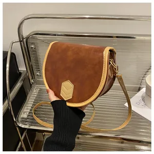 Detailed view of a vintage brown saddle bag with beige contrast trim and gold buckle